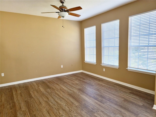 empty room featuring dark wood-style floors, ceiling fan, and baseboards