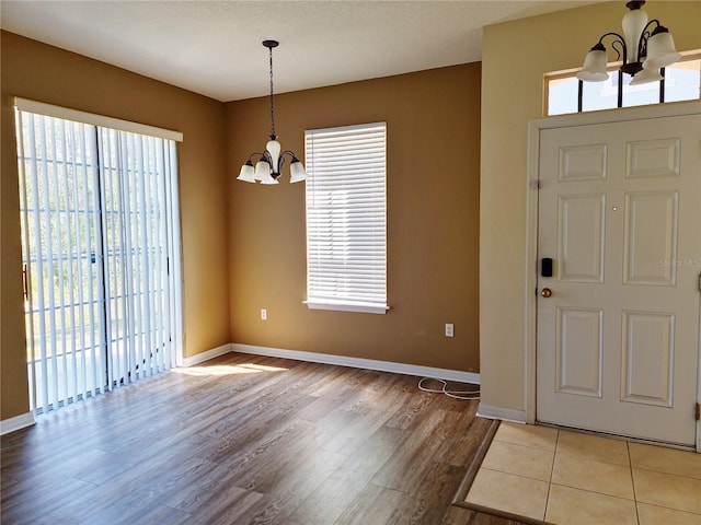 entryway with baseboards, light wood-style floors, and an inviting chandelier