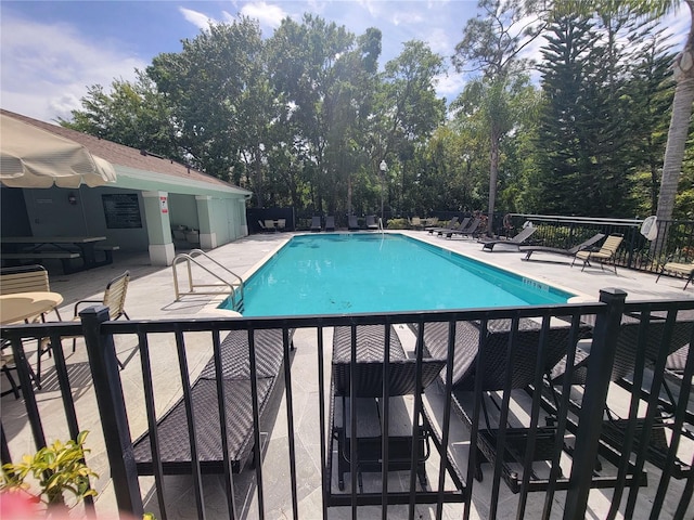 community pool with a patio and fence