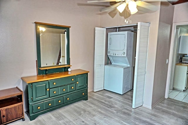 washroom with a ceiling fan, stacked washer / dryer, laundry area, and light wood-style flooring