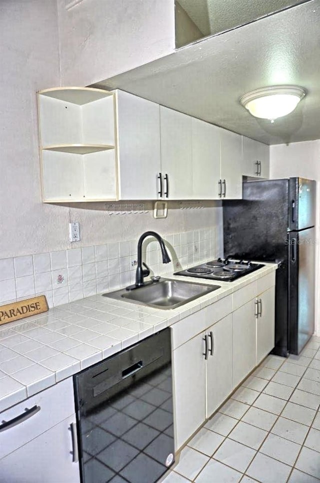 kitchen with a sink, black dishwasher, tile countertops, and white cabinetry