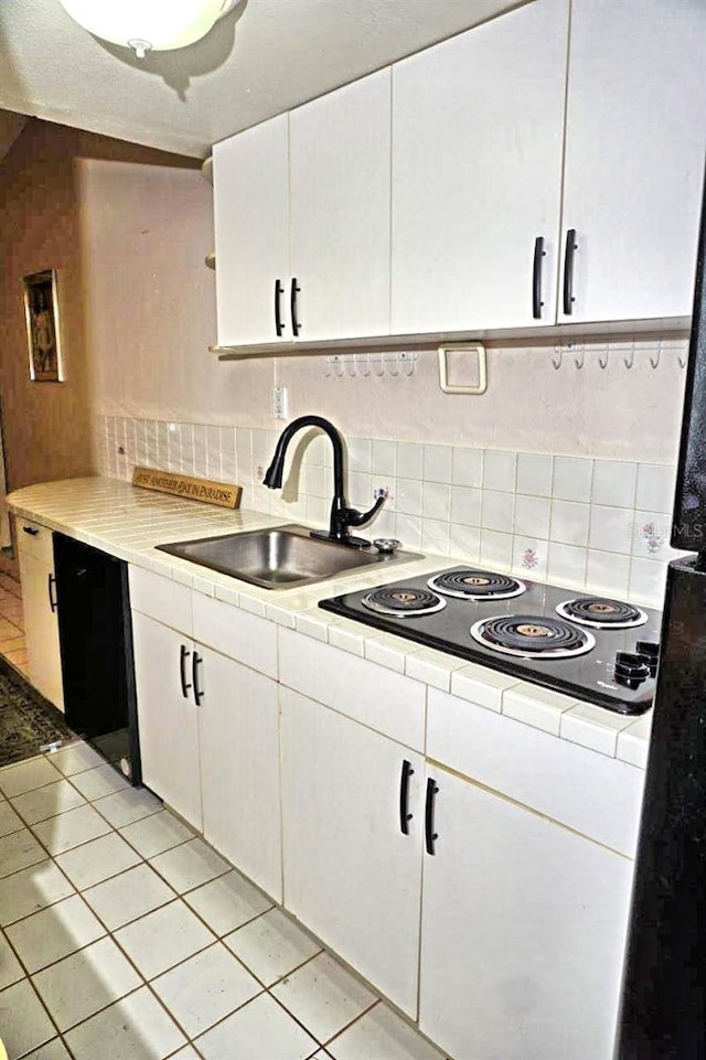 kitchen featuring white cabinetry, a sink, decorative backsplash, and black electric cooktop