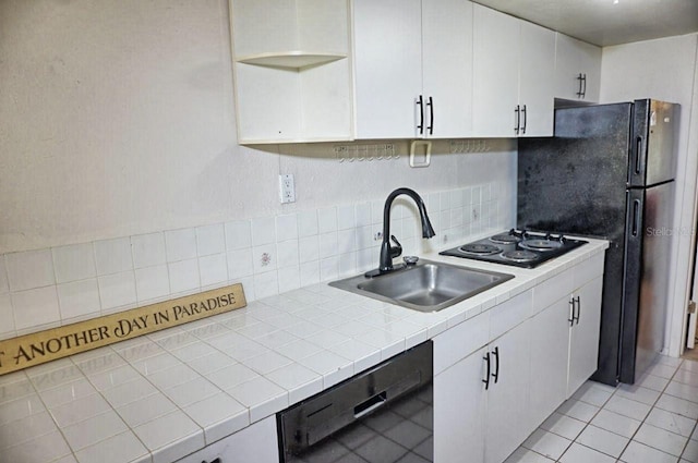 kitchen with white cabinetry, black appliances, light tile patterned floors, and a sink