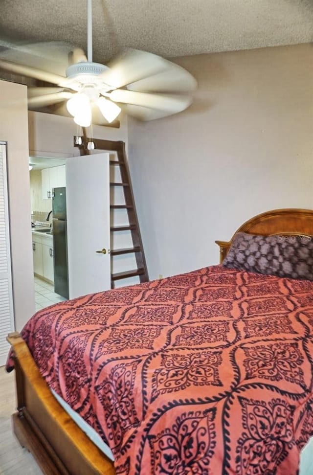 bedroom featuring a ceiling fan, ensuite bathroom, a sink, a textured ceiling, and freestanding refrigerator