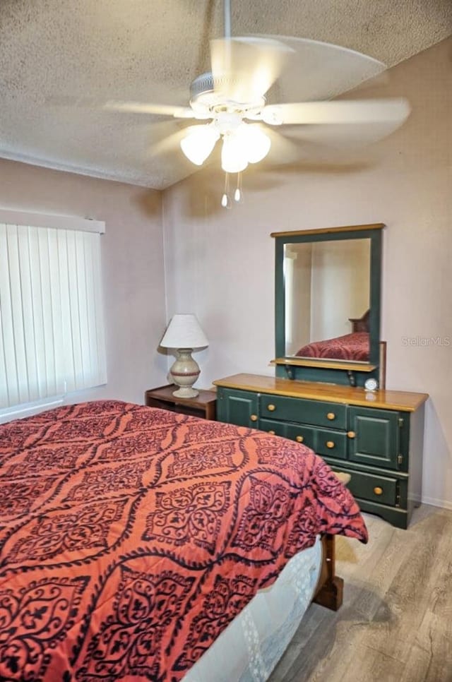 bedroom with baseboards, a textured ceiling, light wood-style flooring, and a ceiling fan