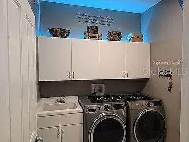 washroom with cabinet space, a sink, and washer and clothes dryer