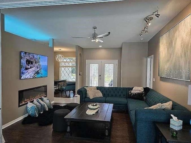 living room with baseboards, a glass covered fireplace, ceiling fan, rail lighting, and french doors