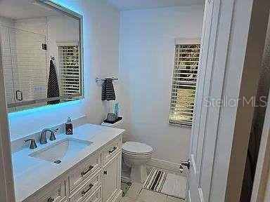 full bathroom with a stall shower, vanity, toilet, and tile patterned floors