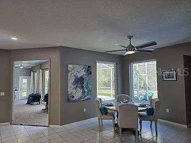 dining area featuring a textured ceiling, light tile patterned floors, a ceiling fan, and baseboards