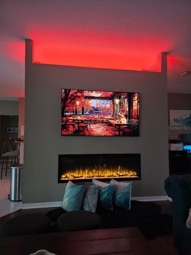 tiled home theater room featuring a warm lit fireplace, baseboards, visible vents, and a textured ceiling