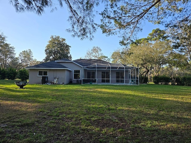 back of house featuring a lawn, a lanai, and stucco siding