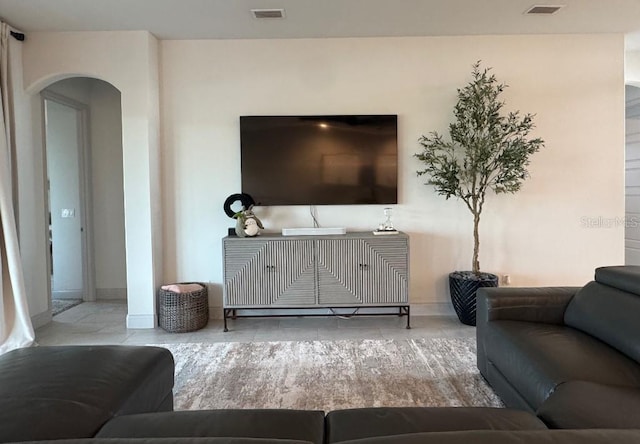 living area with arched walkways, visible vents, and baseboards