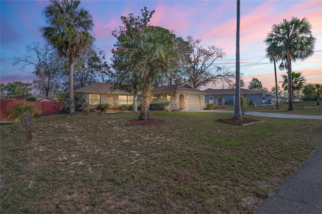 view of front of property featuring a front yard, concrete driveway, fence, and an attached garage