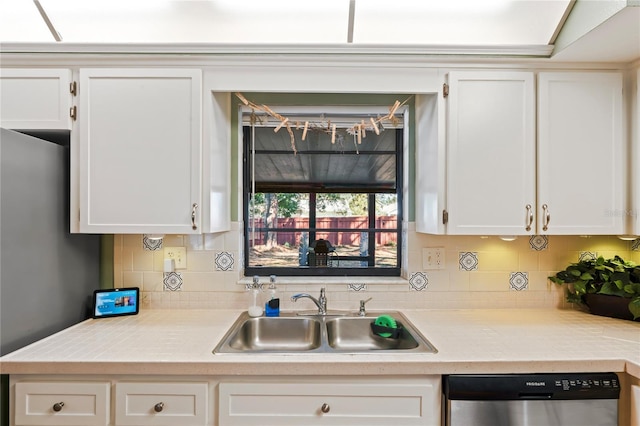 kitchen with light countertops, decorative backsplash, white cabinets, a sink, and dishwasher