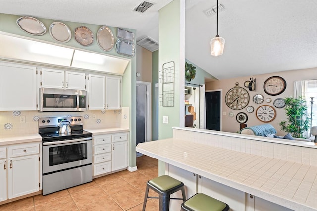 kitchen featuring appliances with stainless steel finishes, backsplash, visible vents, and white cabinetry