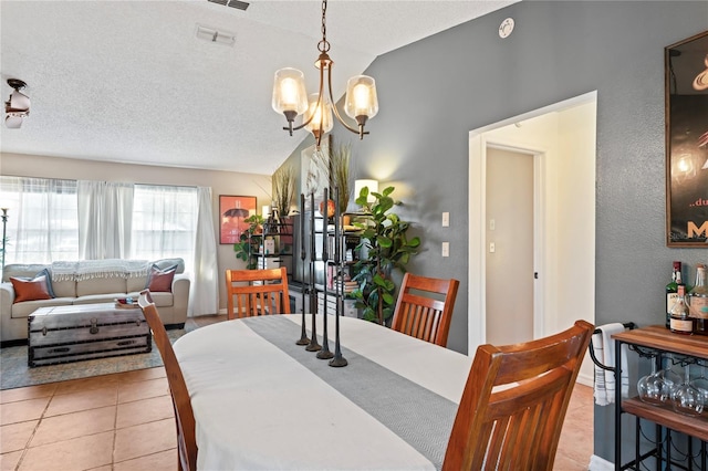 dining space with a textured ceiling, visible vents, vaulted ceiling, tile patterned floors, and an inviting chandelier