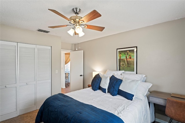 bedroom featuring visible vents, a ceiling fan, light colored carpet, a textured ceiling, and a closet