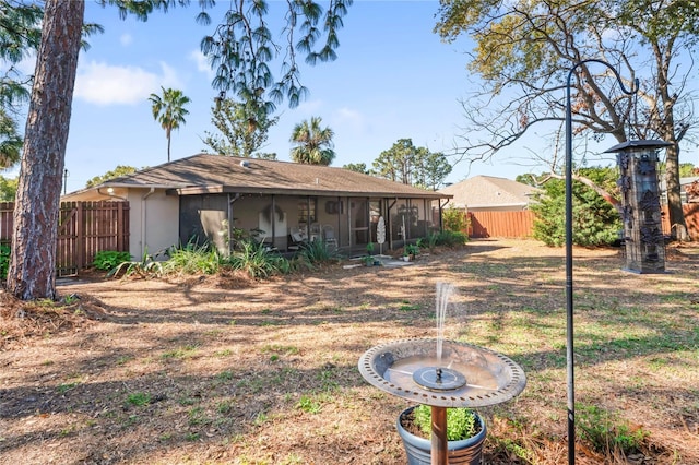 rear view of house with a sunroom, fence, and stucco siding