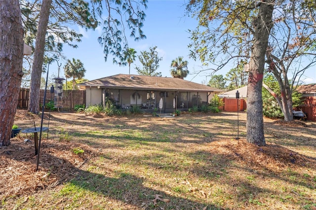 rear view of house with covered porch, fence, and stucco siding