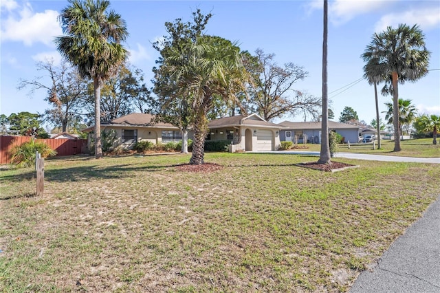 ranch-style house with a garage, driveway, fence, and a front lawn