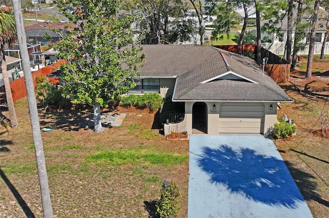 view of front of house with a garage, concrete driveway, roof with shingles, a front yard, and stucco siding