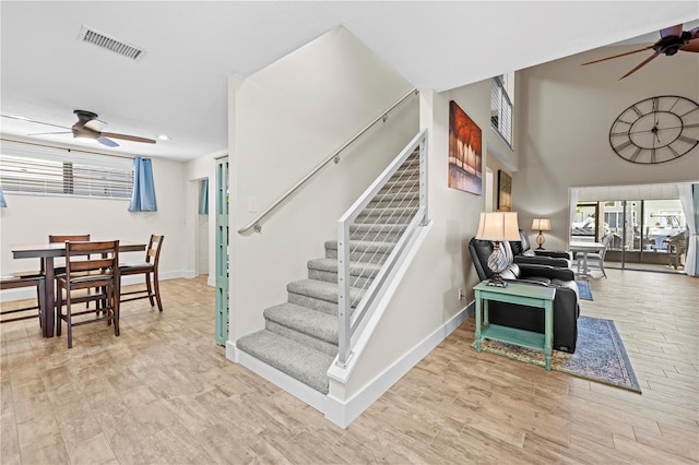 staircase featuring ceiling fan, wood finished floors, visible vents, and baseboards