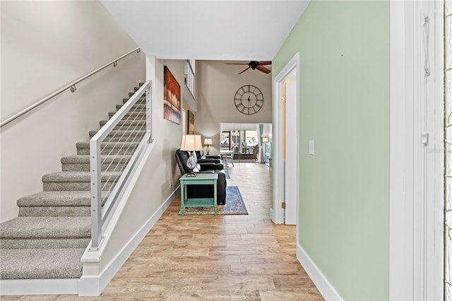 foyer featuring stairs, wood finished floors, a ceiling fan, and baseboards