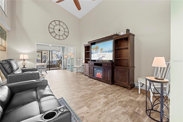 living area with baseboards, light wood-style flooring, high vaulted ceiling, and a ceiling fan