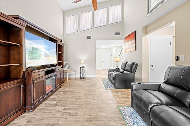 living area with light wood finished floors, baseboards, visible vents, and ceiling fan