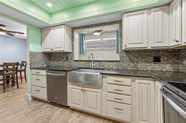 kitchen with stainless steel appliances, dark countertops, a sink, and decorative backsplash