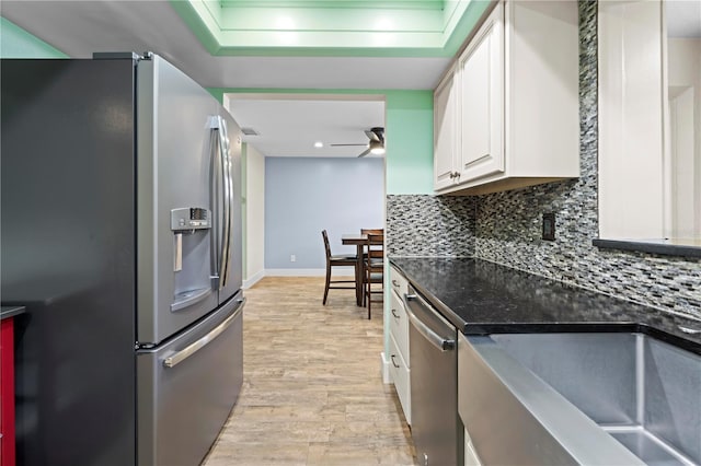 kitchen featuring a sink, white cabinetry, appliances with stainless steel finishes, light wood-type flooring, and tasteful backsplash