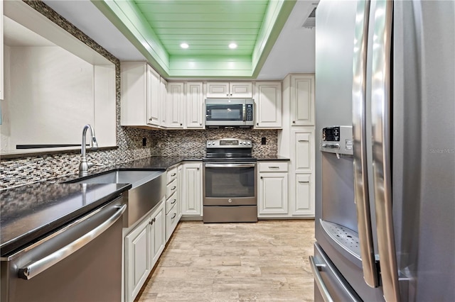 kitchen featuring stainless steel appliances, white cabinets, a sink, and backsplash