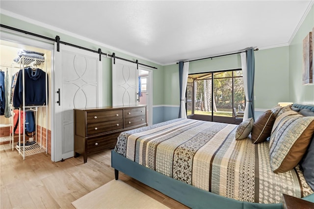 bedroom featuring light wood-style floors, ornamental molding, and a barn door