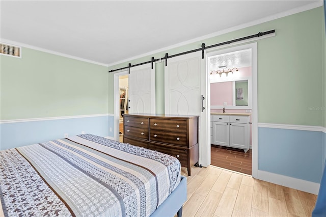 bedroom featuring a barn door, visible vents, ornamental molding, and wood finish floors