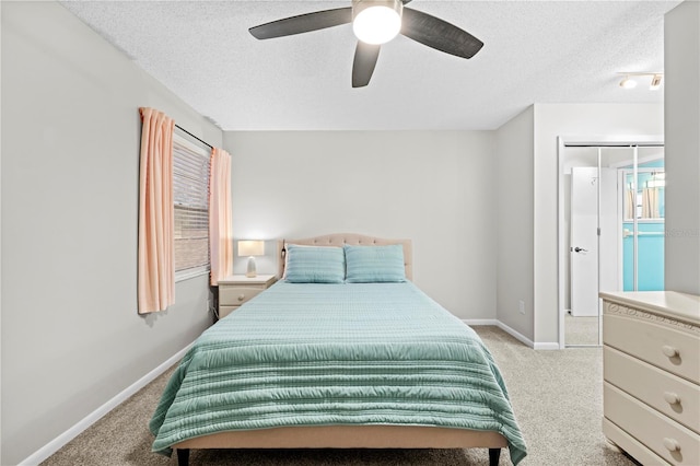 carpeted bedroom featuring ceiling fan, a textured ceiling, and baseboards