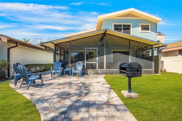 back of property with a sunroom, stucco siding, a patio, and a yard