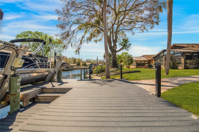 wooden terrace featuring a dock, a water view, and a lawn