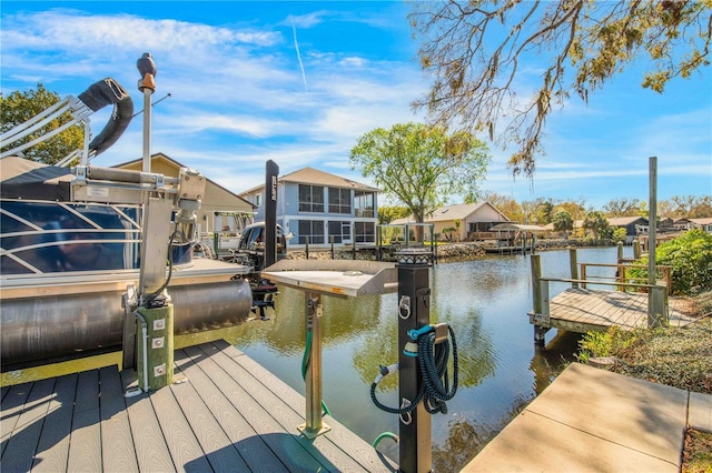 view of dock featuring a water view, boat lift, and a residential view