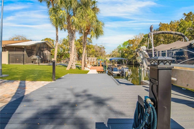 view of dock with fence and a lawn