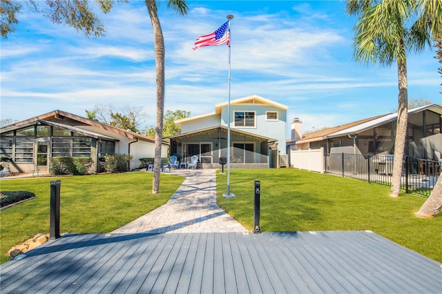 rear view of house featuring a sunroom, a fenced backyard, and a lawn