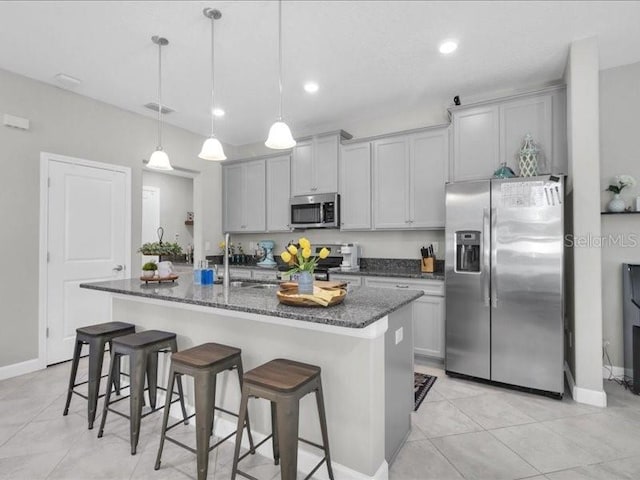 kitchen with stainless steel appliances, a breakfast bar, a sink, and a kitchen island with sink