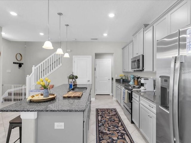 kitchen featuring recessed lighting, stainless steel appliances, a sink, a kitchen bar, and a center island with sink