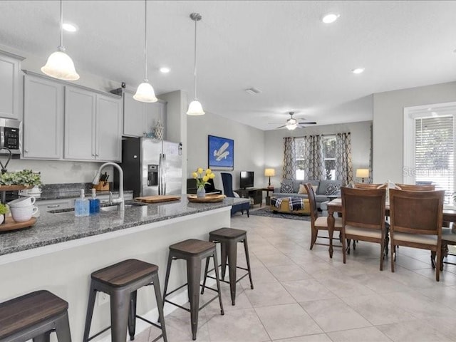 kitchen featuring stainless steel appliances, a healthy amount of sunlight, a sink, and a kitchen bar