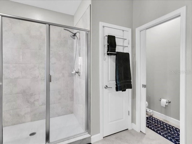 bathroom featuring baseboards, a shower stall, and toilet