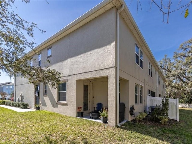 view of property exterior with fence, a lawn, and stucco siding