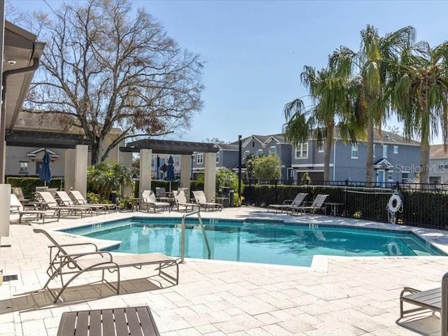 community pool with a patio area, fence, a residential view, and a pergola