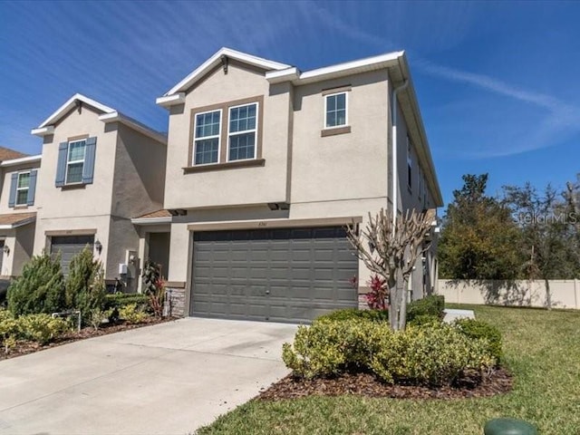 traditional-style house featuring stucco siding, concrete driveway, fence, a garage, and a front lawn