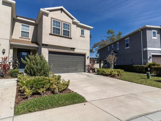 view of front of home featuring concrete driveway, an attached garage, and stucco siding