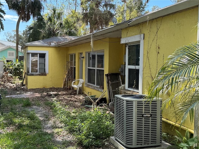 exterior space featuring electric meter, cooling unit, and stucco siding