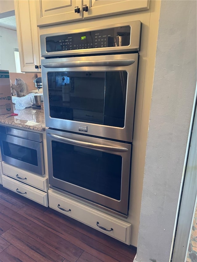 interior details featuring light stone countertops, dark wood-style flooring, and stainless steel double oven